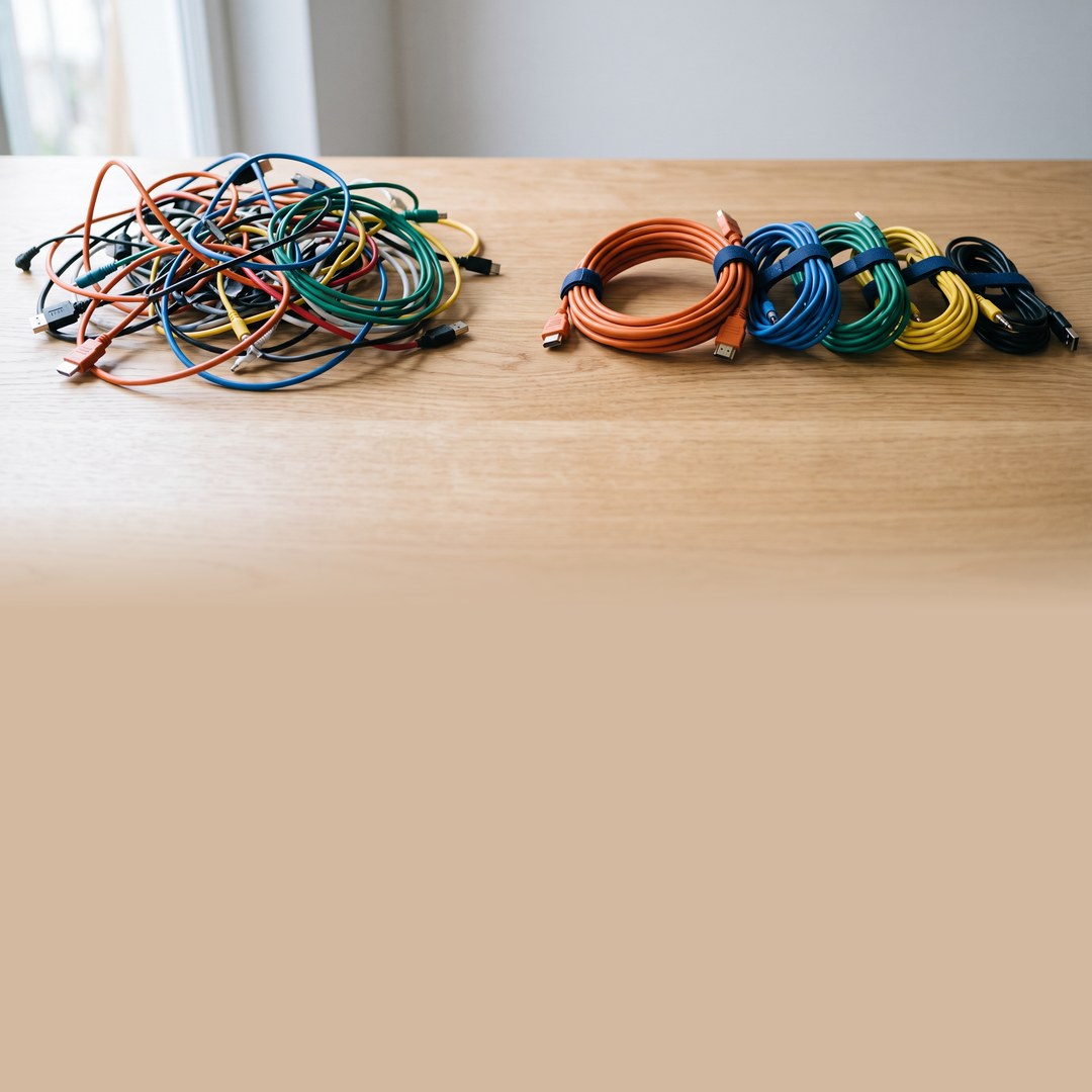 On the left is a tangled mess of cables; on the right, the same cables neatly rolled up and tied with dark blue ribbons.
